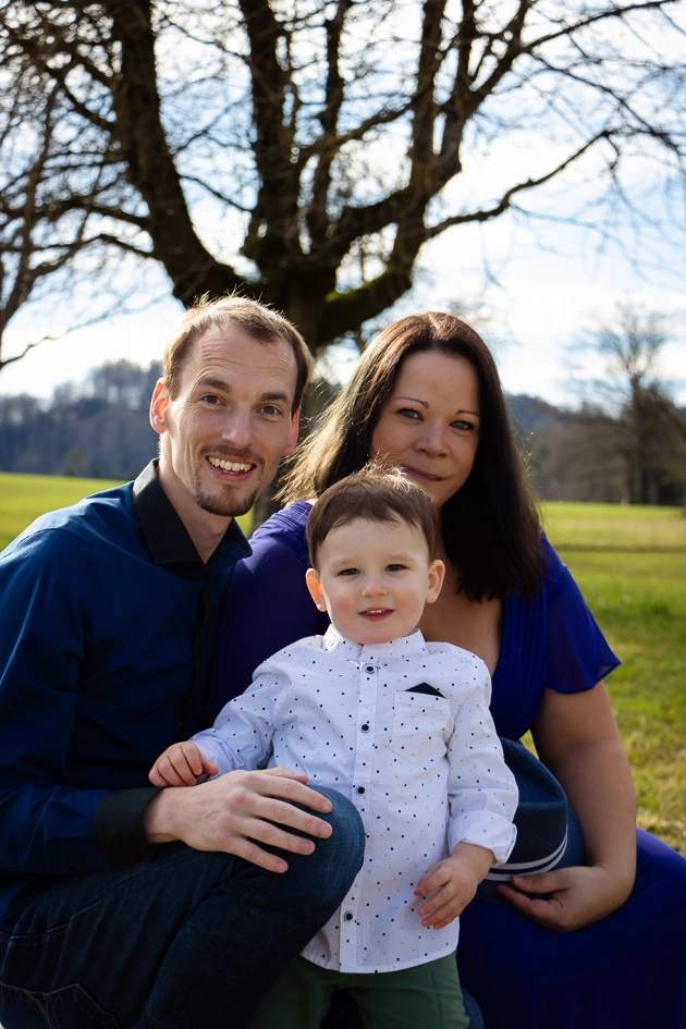 Familienfotografie: Mutter und Vater sitzen mit ihrem Baby