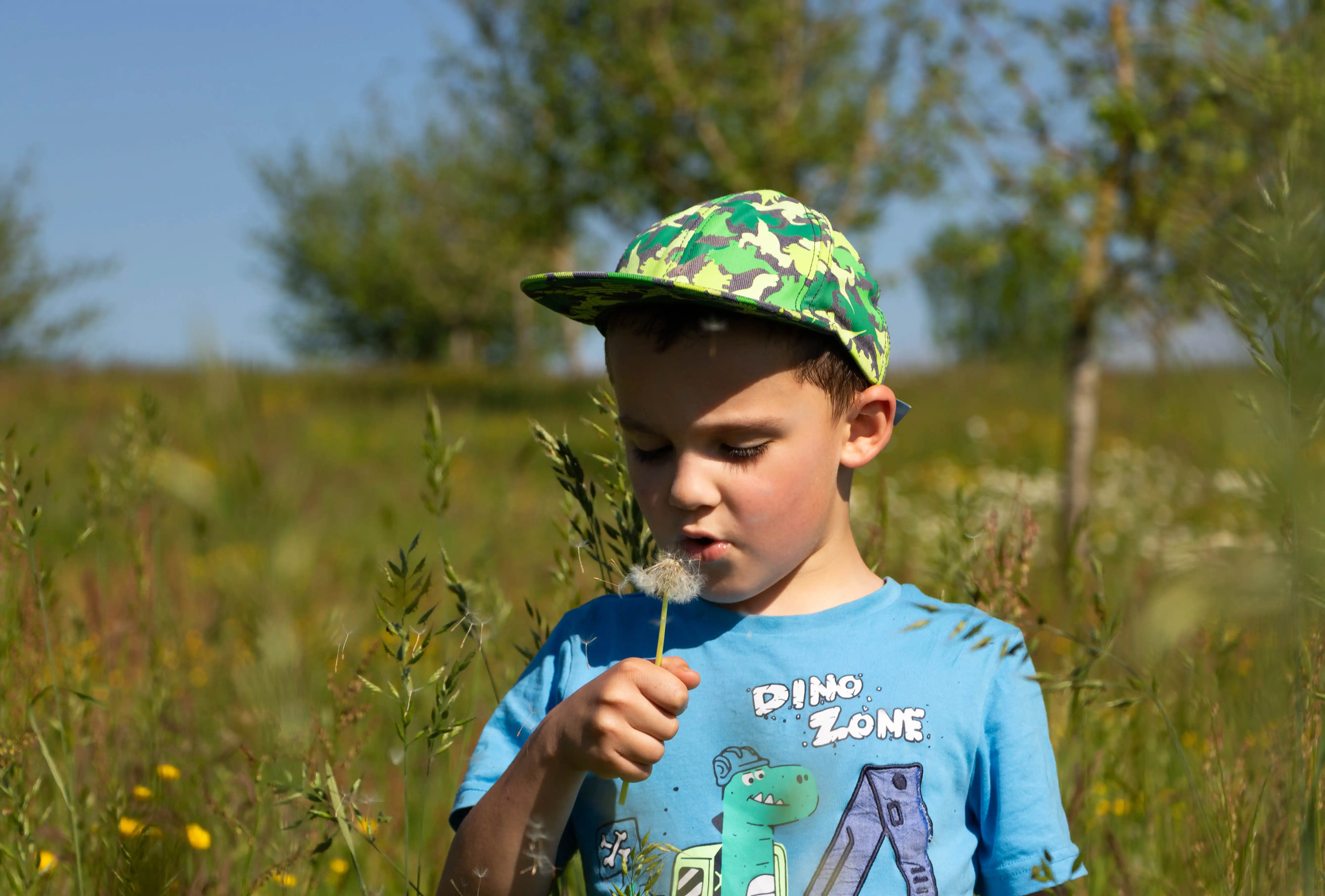 Kinderfotografie: Kind in der Natur mit Pusteblume in der Hand