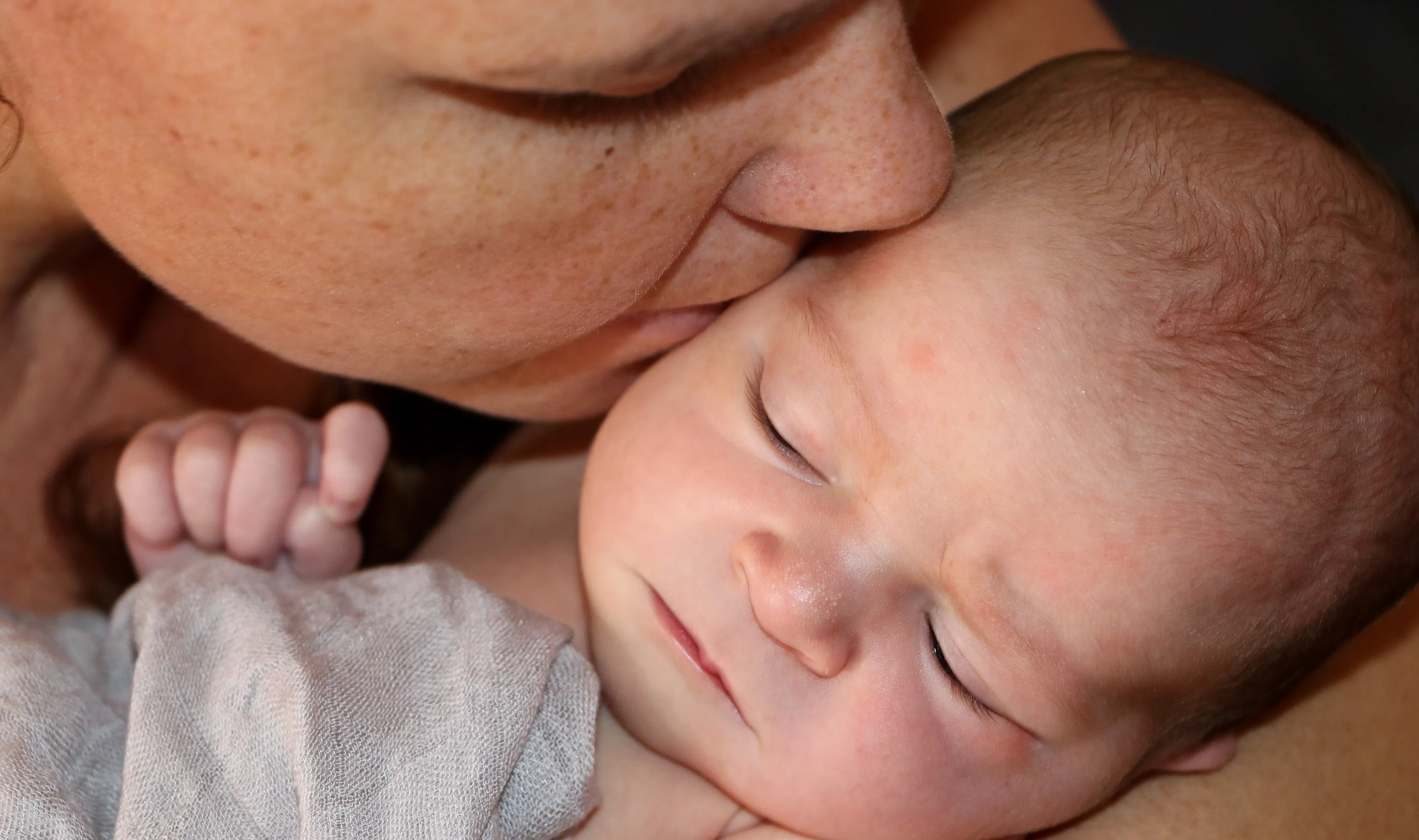 Mutter küsst ihr neugeborenes Baby beim Shooting